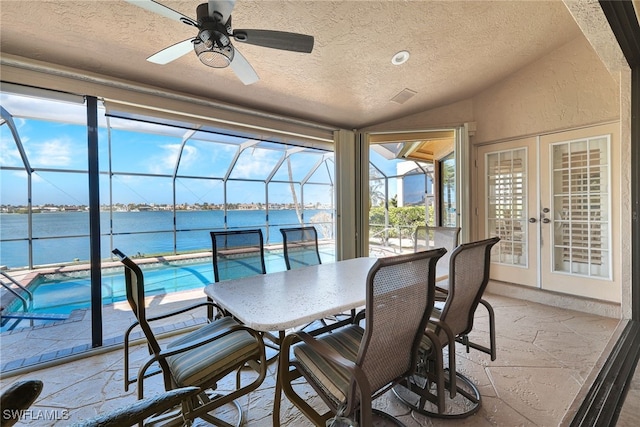 sunroom / solarium featuring vaulted ceiling, french doors, ceiling fan, and a water view