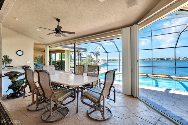 sunroom / solarium with a water view, ceiling fan, and lofted ceiling