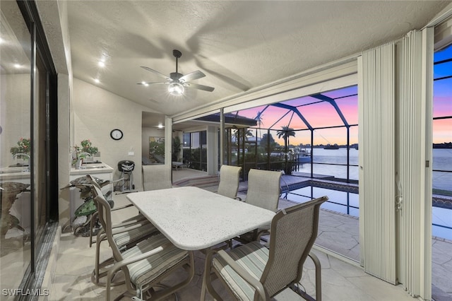 interior space featuring vaulted ceiling, ceiling fan, a water view, and a textured ceiling