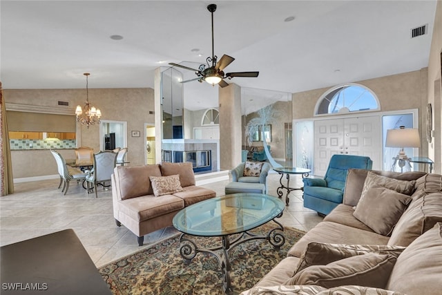 tiled living room featuring ceiling fan with notable chandelier and high vaulted ceiling