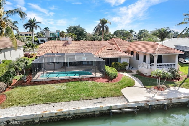 rear view of property with a water view, a yard, and glass enclosure