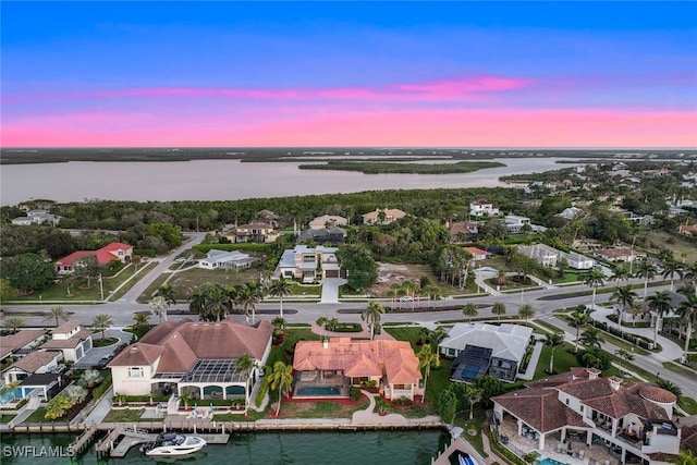 aerial view at dusk featuring a water view