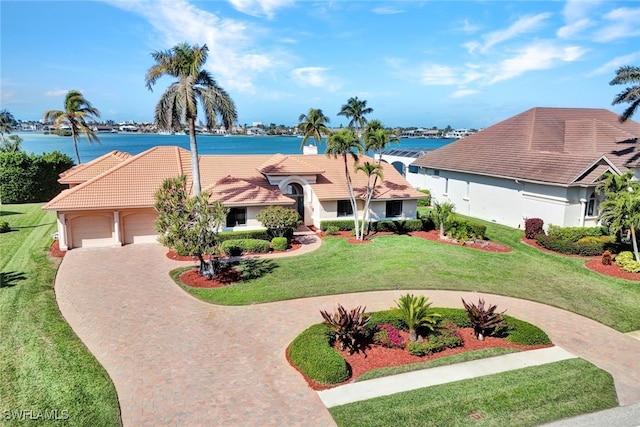 view of front of property with a garage, a water view, and a front yard