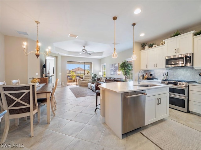 kitchen featuring white cabinetry, appliances with stainless steel finishes, pendant lighting, and an island with sink