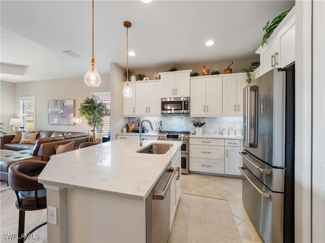 kitchen with high end appliances, light stone counters, pendant lighting, and white cabinets