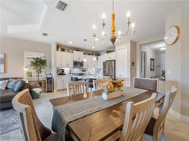 dining room with an inviting chandelier, beverage cooler, sink, and light tile patterned floors