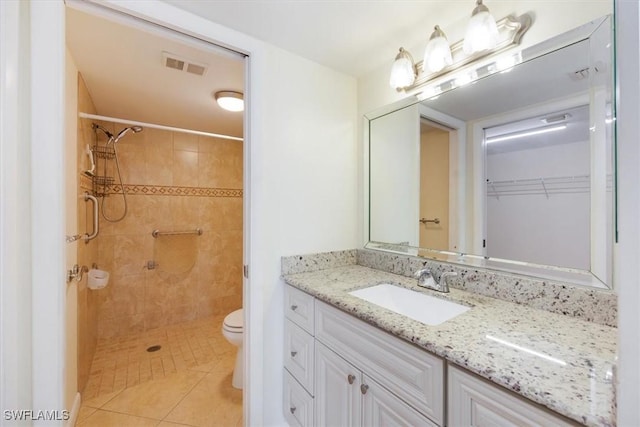 bathroom with vanity, tiled shower, toilet, and tile patterned floors