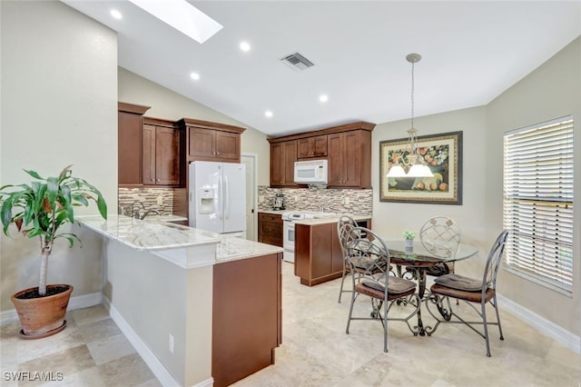 kitchen with decorative light fixtures, kitchen peninsula, white appliances, vaulted ceiling with skylight, and backsplash