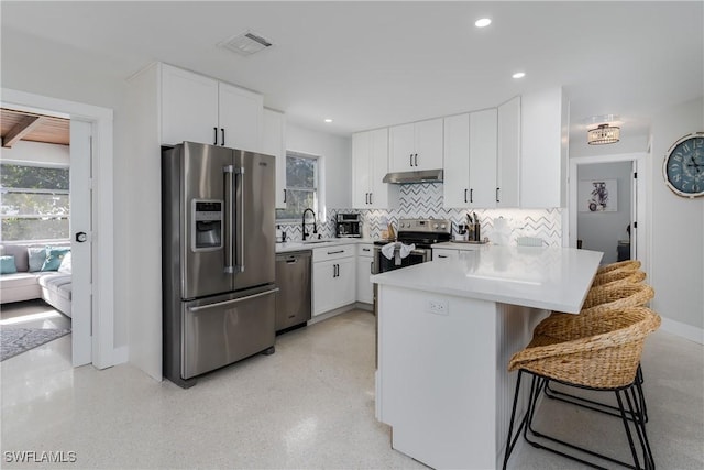 kitchen featuring appliances with stainless steel finishes, a breakfast bar, kitchen peninsula, and white cabinets