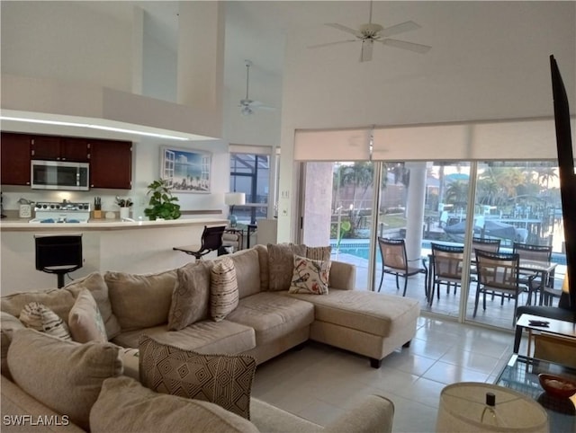 tiled living room with a towering ceiling and ceiling fan