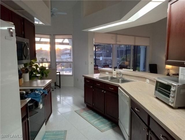 kitchen featuring light tile patterned flooring, sink, ceiling fan, kitchen peninsula, and white appliances