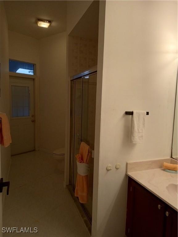 bathroom featuring an enclosed shower, vanity, tile patterned floors, and toilet