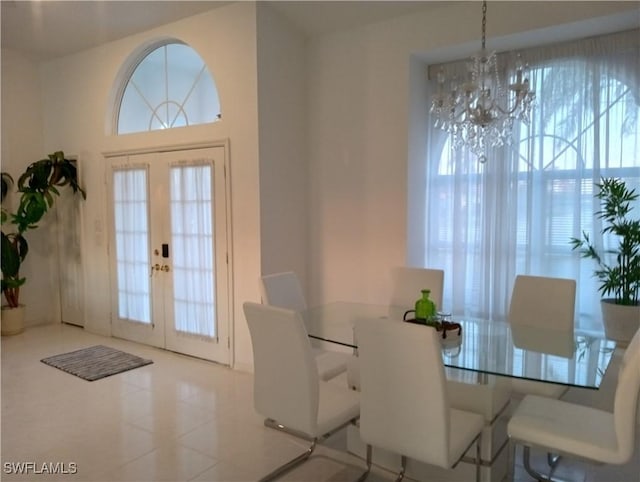 dining room with a notable chandelier, light tile patterned floors, and french doors