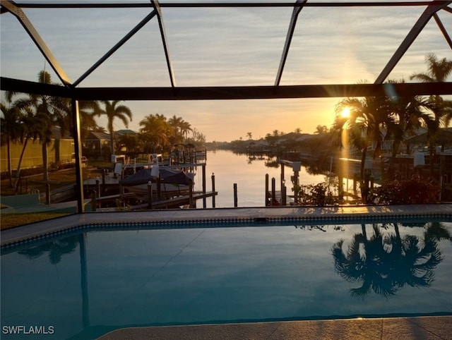 pool at dusk featuring a boat dock, glass enclosure, and a water view