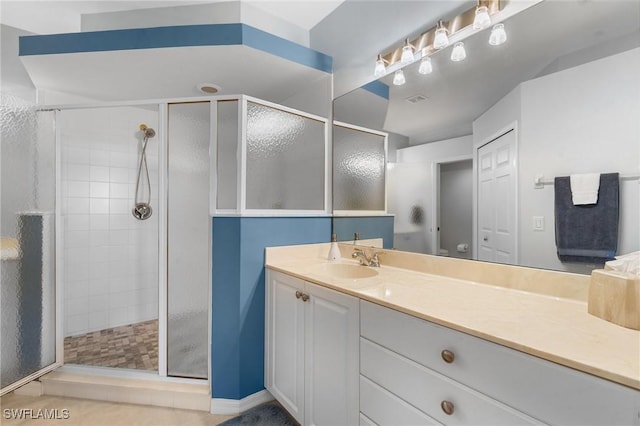 bathroom with tile patterned flooring, vanity, and walk in shower