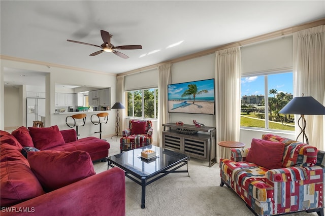 living room featuring ceiling fan, ornamental molding, and light carpet