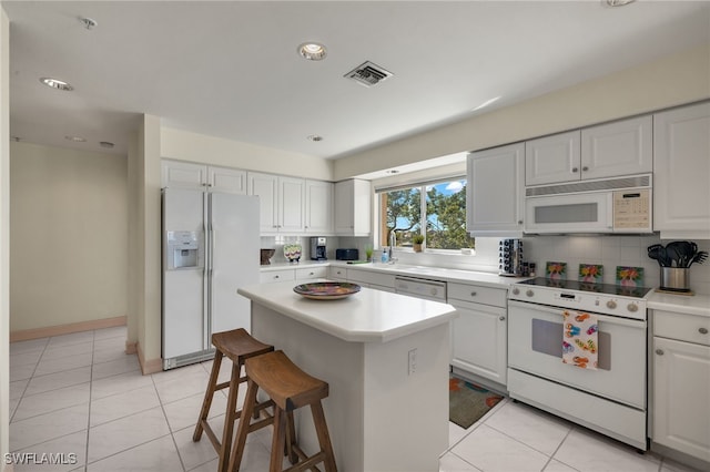 kitchen featuring white cabinetry, white appliances, a center island, and light tile patterned flooring