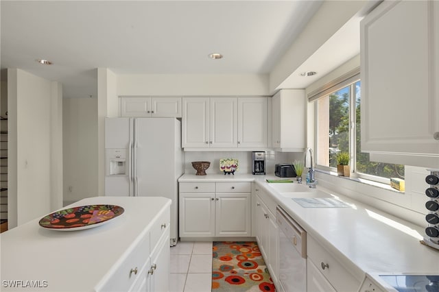 kitchen with white appliances, a wealth of natural light, light tile patterned floors, and white cabinets