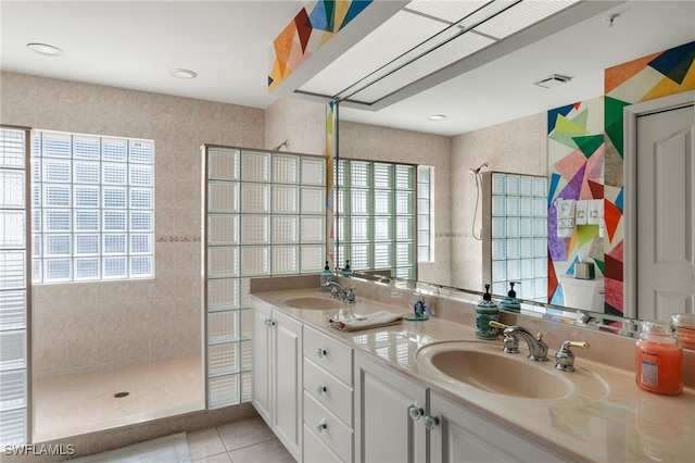 bathroom featuring tile patterned flooring, vanity, and a tile shower