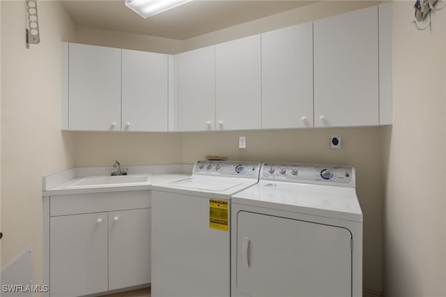 clothes washing area featuring cabinets, sink, and washing machine and dryer