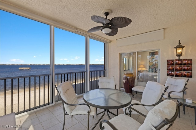 sunroom / solarium with a water view and ceiling fan