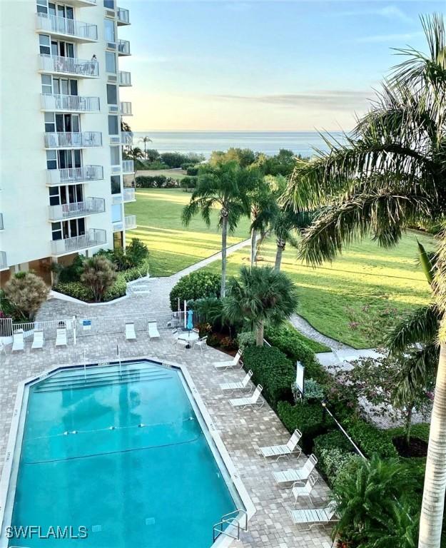 view of pool featuring a water view, a yard, and a patio area