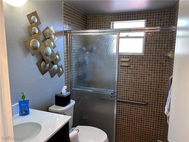 bathroom featuring vanity, toilet, and a shower with door