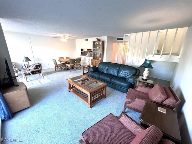 carpeted living room with ceiling fan and a textured ceiling