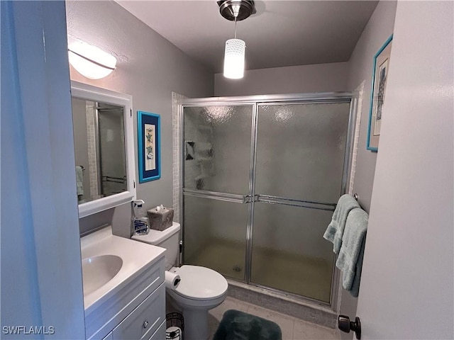 bathroom with tile patterned floors, vanity, toilet, and a shower with shower door