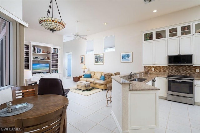 kitchen with stainless steel range with electric cooktop, light stone counters, decorative light fixtures, kitchen peninsula, and white cabinets