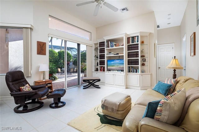 sitting room with light tile patterned floors, ceiling fan, and a high ceiling