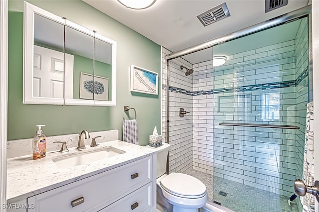 bathroom with a shower with door, vanity, and toilet