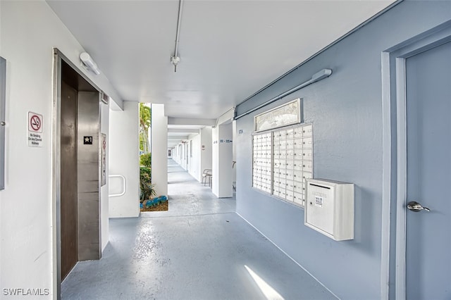 hallway featuring elevator and a mail area