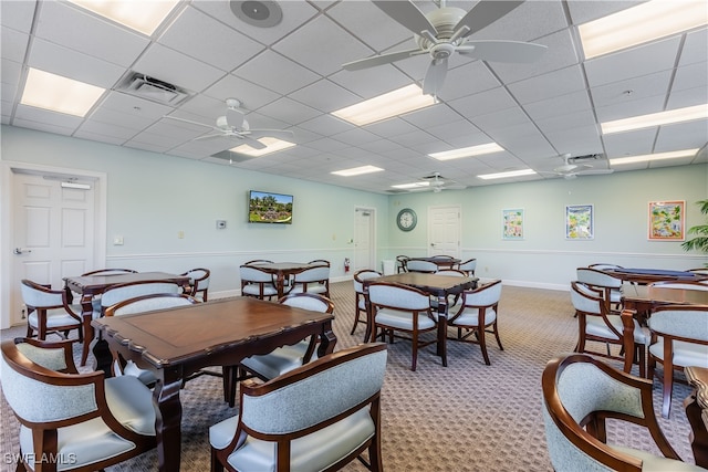 carpeted dining area with ceiling fan and a paneled ceiling