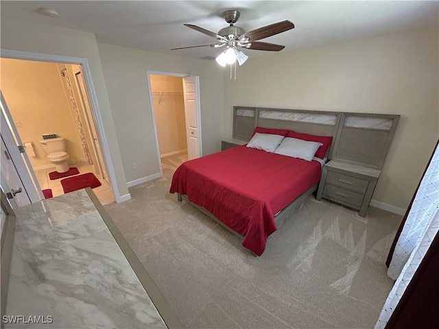 bedroom featuring ensuite bathroom, a spacious closet, light carpet, and ceiling fan