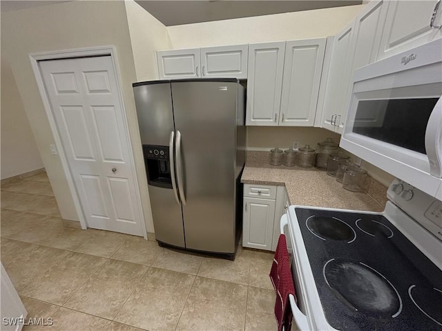 kitchen with white appliances, light tile patterned floors, and white cabinets