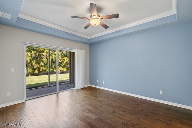 spare room with dark wood-type flooring, ceiling fan, a tray ceiling, and crown molding