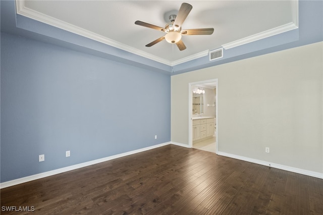 empty room with dark wood-type flooring, ceiling fan, a tray ceiling, and crown molding