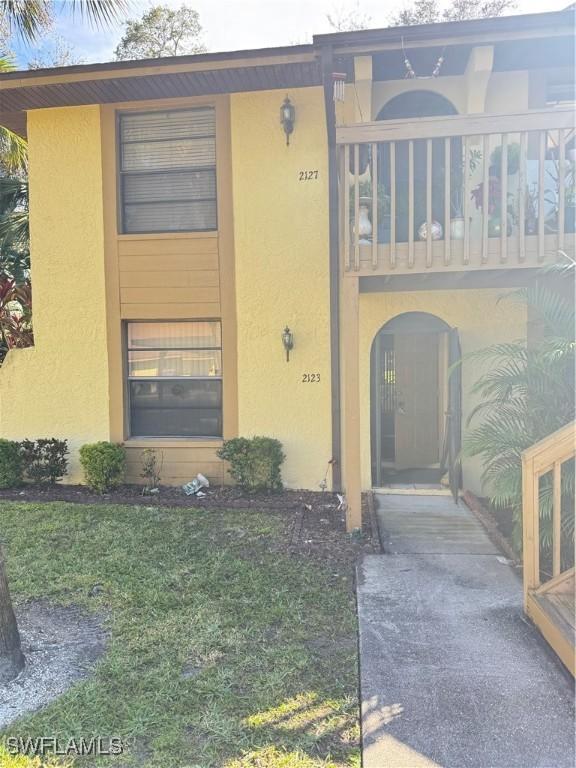 view of front of property featuring a balcony and a front yard