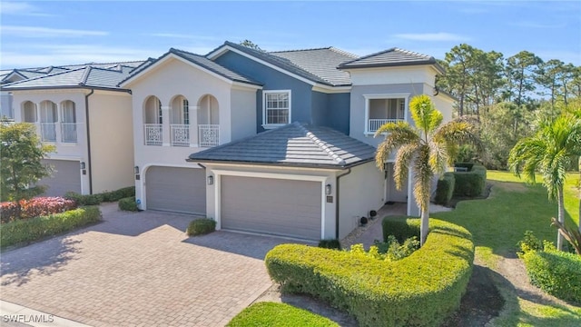 view of front of house featuring decorative driveway, a front yard, stucco siding, and a tiled roof