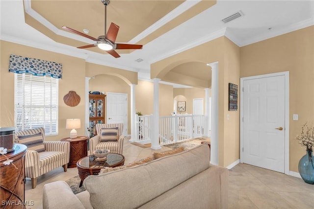 tiled living room with ornate columns, a raised ceiling, ceiling fan, and crown molding