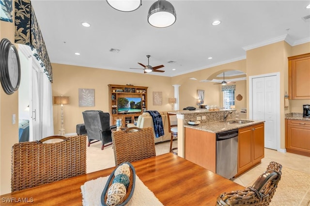 kitchen with sink, dishwasher, ceiling fan, light stone countertops, and a kitchen island with sink