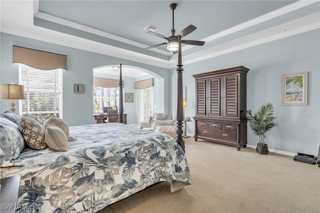 carpeted bedroom featuring a raised ceiling, crown molding, and ceiling fan