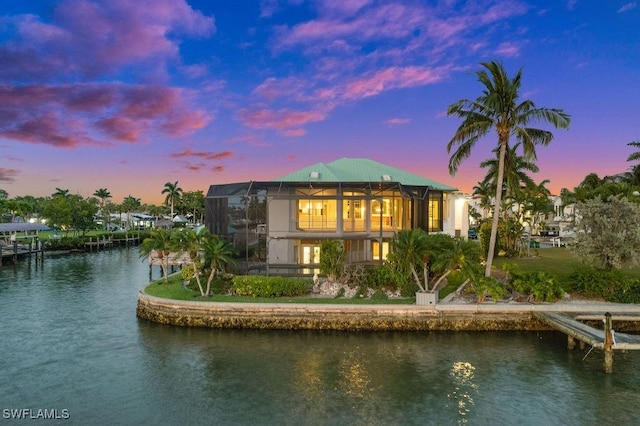 back house at dusk with a lanai and a water view