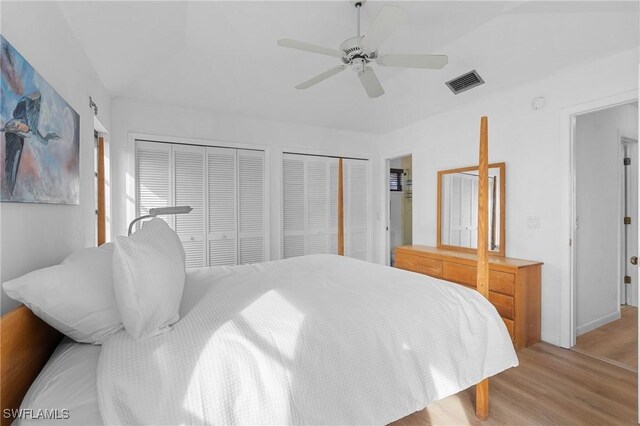 bedroom featuring multiple closets, ceiling fan, and light wood-type flooring