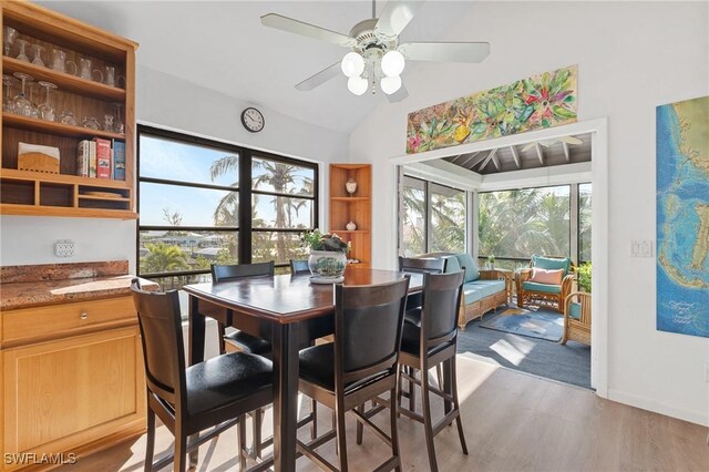 dining room with light hardwood / wood-style flooring, ceiling fan, and vaulted ceiling