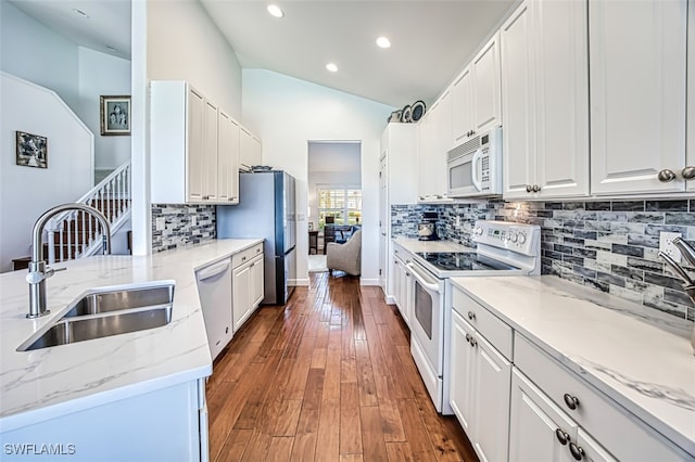 kitchen featuring lofted ceiling, sink, white appliances, white cabinetry, and light stone countertops