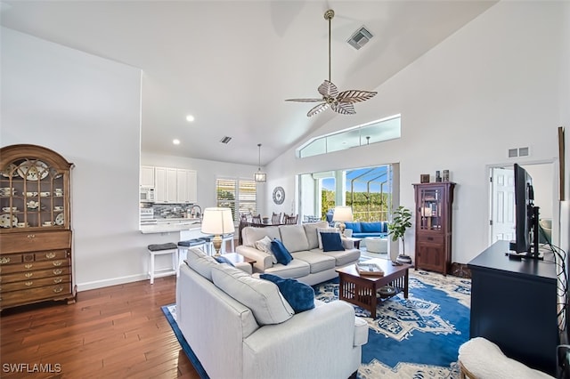 living room with dark wood-type flooring, ceiling fan, and high vaulted ceiling