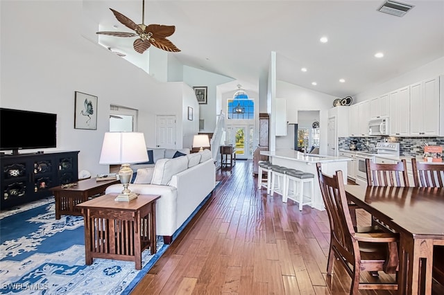 living room with sink, wood-type flooring, high vaulted ceiling, and ceiling fan