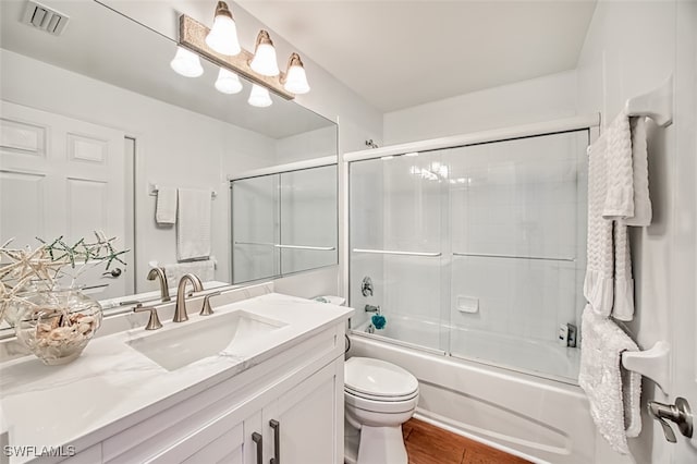 full bathroom with shower / bath combination with glass door, vanity, toilet, and hardwood / wood-style floors